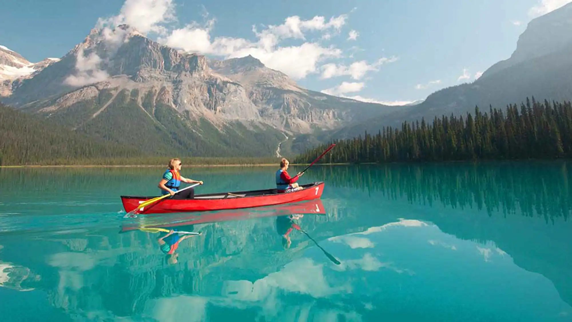two friends canoeing on a mountain lake