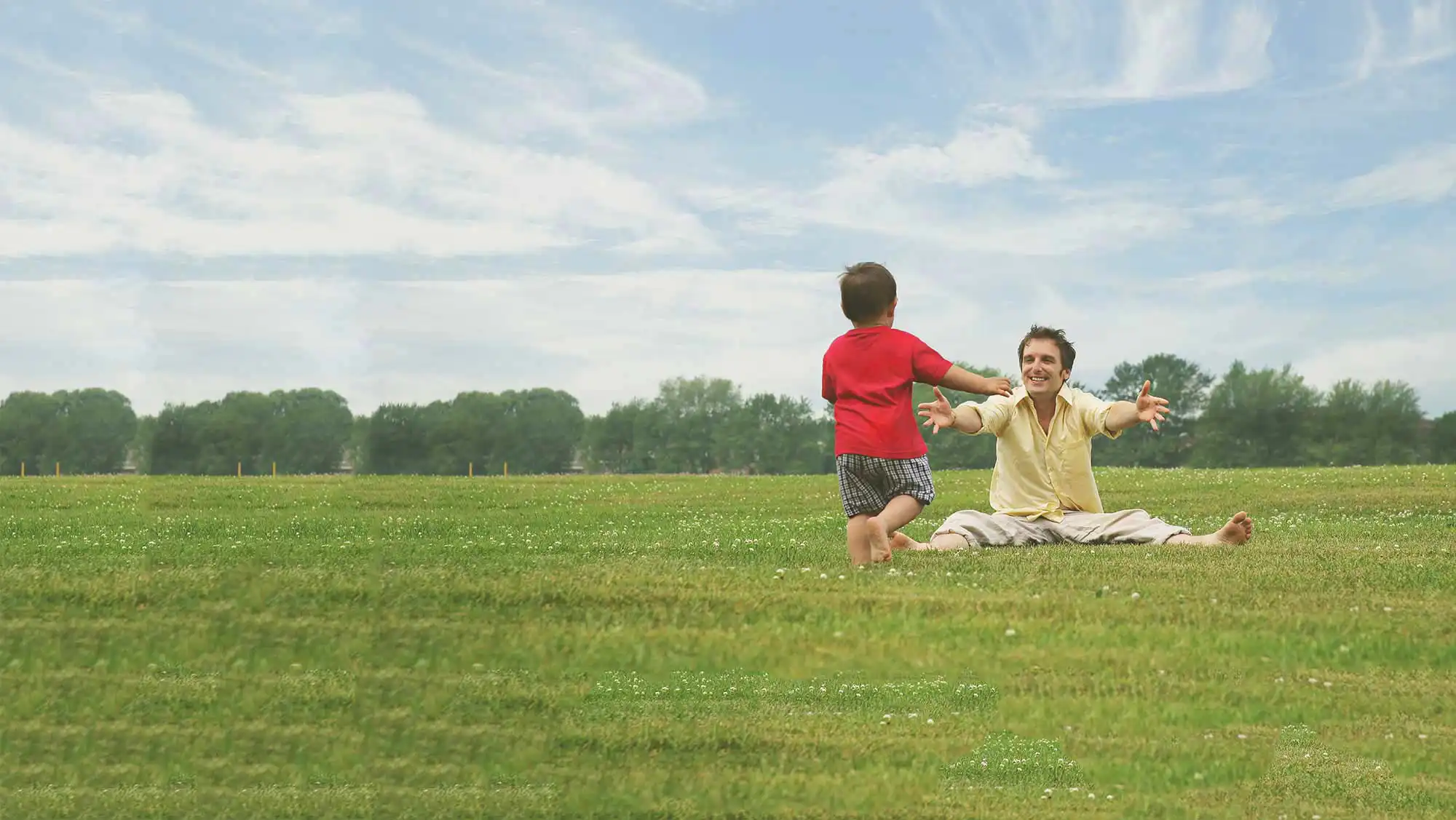 dad playing with his young son on the grass